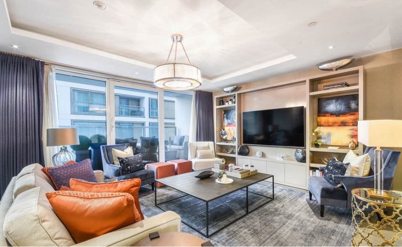 Living area with orange accent cushions and media wall